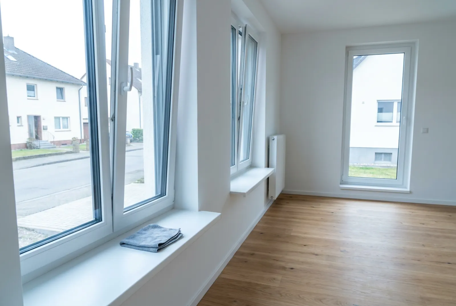 Leere Neubauwohnung nach der Bauendreinigung mit staubfreiem Holzboden und abgewischten Fensterbänken