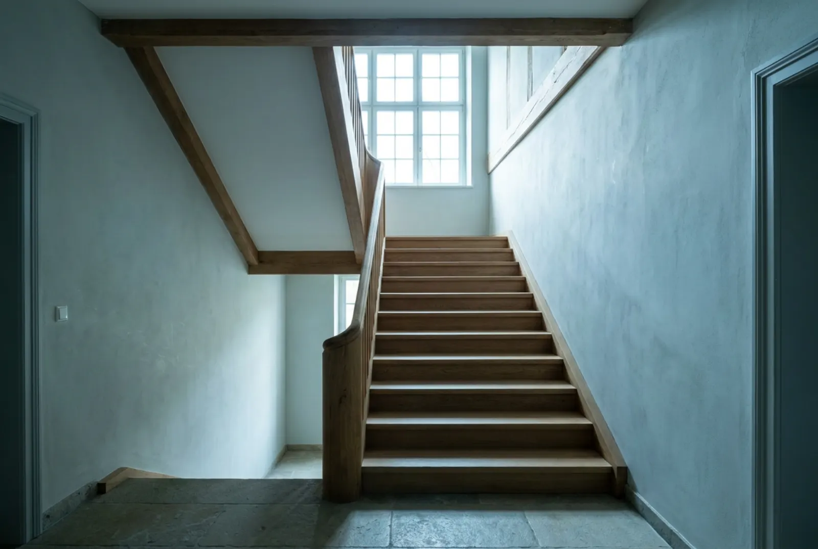 Massive Eichentreppe mit Handlauf im Flur eines Hauses, Licht vom Fenster am Treppenabsatz