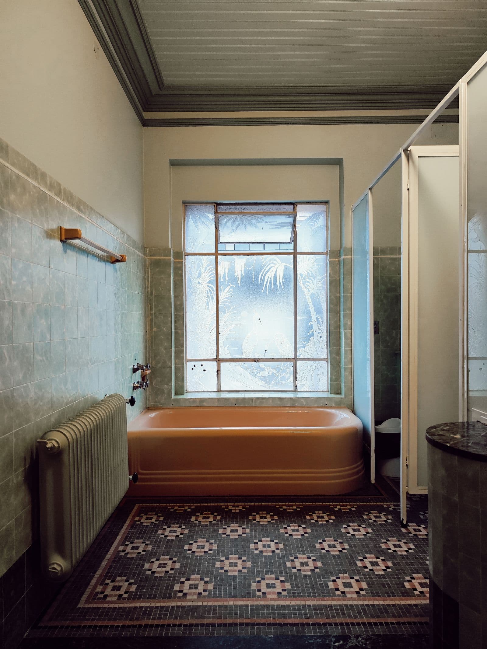 Altbau-Bad mit Wandfliesen, Gliederheizkörper und farbiger Wanne