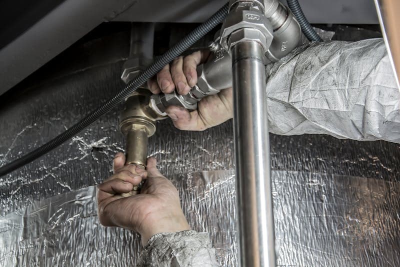 Installateur arbeitet an Rohrleitungen im Bad